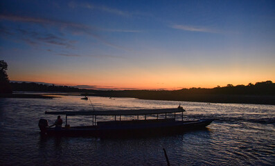 Longtail boat on the Tambopata River on a sunset, Tambopata National Reserve, Peruvian Amazon 