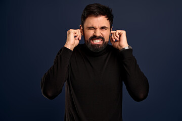 Young man with stylish hair covering his ears and shouting. Went into hysterics because of argument...
