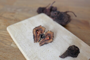 Aufgeschnittene Kletzen (Dörrbirne) auf dem Schneidbrett mit Kletten im Vorder- und Hintergrund.