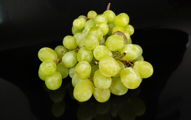 Branch of ripe green grapes isolated on a black background. Selective focus on the green grape