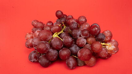 Fresh red grapes isolated on pink background. Selective focus on the fresh red grapes.
