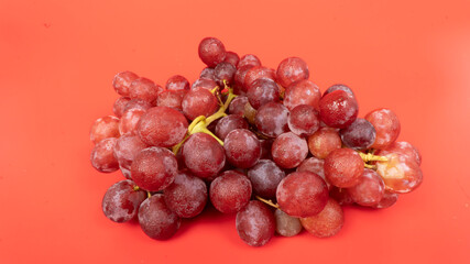 Fresh red grapes isolated on pink background. Selective focus on the fresh red grapes.