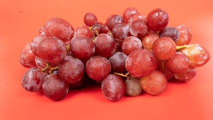 Fresh red grapes isolated on pink background. Selective focus on the fresh red grapes.