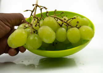 Fresh green grapes in a bowl isolated on pink background. Selective focus on the fresh green grapes.