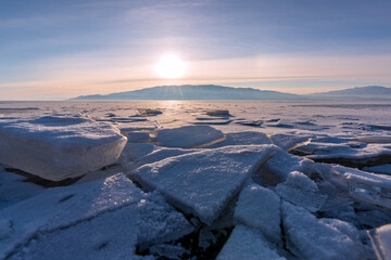 Ice chunks build up on the shore of frozen Utah Lak at sunrset.