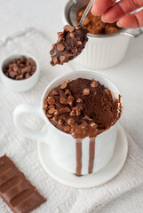 Chocolate mug cake in white cup with chocolate drops and coca powder