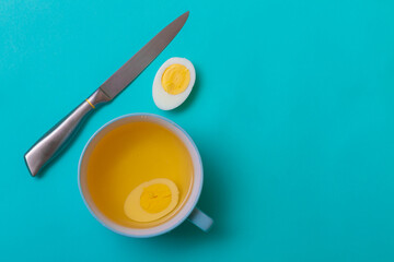 Chicken broth in a plate and boiled chicken egg in soup