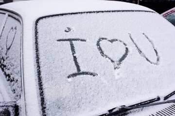 I love you Heart symbol on frozen window of the car. Shape of heart drawn on snow on front window of the car. Heart snow. Christmas decorations and accessories