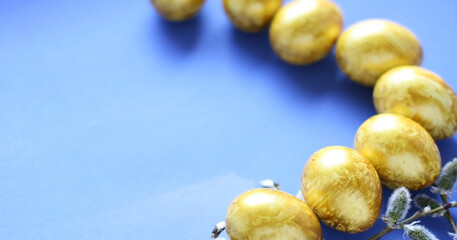 Easter background with golden eggs and willow on a blue background. Template for poster, advertisement, poster, postcard. Happy Easter background top view, copy space