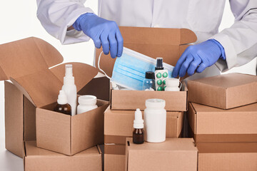 Pharmacist putting a face mask into a box with remedies