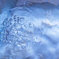 Square background of blue frozen water with bubbles and drops.
