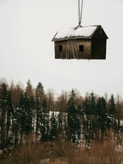 Vertical shot of a wooden nest hanging above the forest with chains