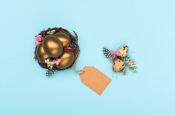 Easter Decoration with golden eggs, quail feathers, dried flowers on blue background. Happy Easter...