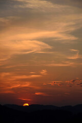 Obraz premium sunset with orange glowing sun and much empty space in the sky