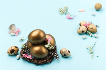 Easter Decoration with golden eggs, quail feathers, dried flowers on blue background. Happy Easter card concept.