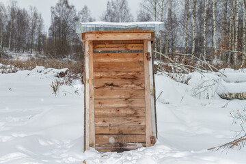 Wooden toilet in nature in winter without a door in the snow.