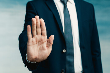 Businessman gesture. Male palm close-up in a gesture of stop. In the background a man in a blue...