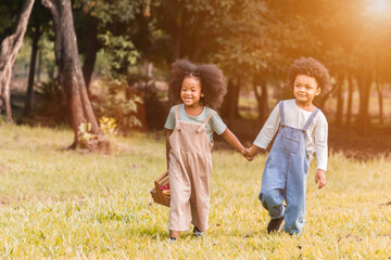 Fototapeta premium Portrait of two adorable african children, girl and boy holding hand and walking together in garden.