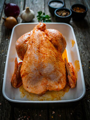 Fresh raw chicken on wooden table prepared to roast

