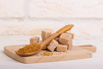 Pricked cane sugar and sugar in a spoon on a wooden board