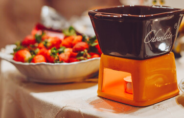 Chocolate fondue with fresh strawberries on the background of a Christmas tree.