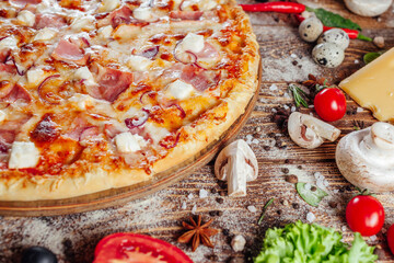 The pizza is surrounded by raw ingredients on the boards