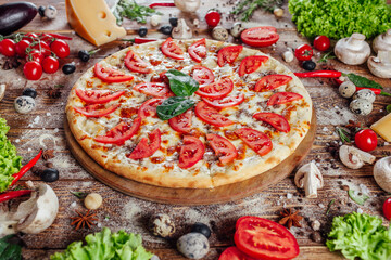 The pizza is surrounded by raw ingredients on the boards