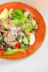 Vegetable vegetarian salad with tomatoes, peppers and onions on white table.