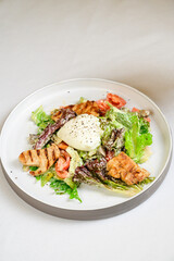Caesar salad with croutons, quail eggs, cherry tomatoes and grilled chicken in white table