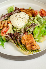 Caesar salad with croutons, quail eggs, cherry tomatoes and grilled chicken in white table
