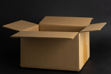 Cardboard shipping box in front of a dark neutral black background. Perfect for packaging for delivery. Empty brown open carton.