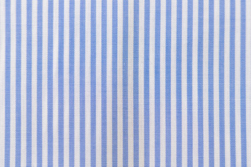 Striped textile pattern of a blue white business shirt. Fabric structure closeup of fashion clothing.