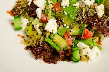 Vegetable vegetarian salad with tomatoes, peppers and onions on white table.