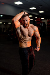 Fototapeta na wymiar Attractive bodybuilder sportsman shows perfect body muscles on gym background. Fitness man. Bodybuilding and gym sport.