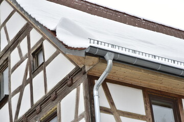 Schneefanggitter zur Vermeidung von Dachlawinen auf dem Ziegeldach eines Fachwerkhauses montiert
