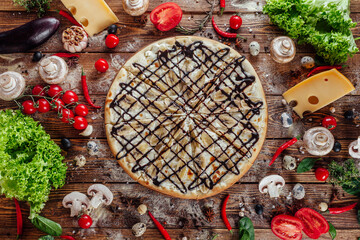 The pizza is surrounded by raw ingredients on the boards