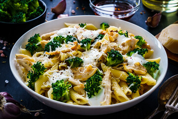 Penne with roast chicken meat, broccoli, parmesan and cream sauce  on black wooden table