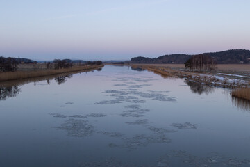 Gota river in western sweden with sheets of ice flowing in the water and hoar frost on the ground
