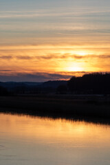 Fototapeta na wymiar Sunset over Gota river in western Sweden. Treeline is reflecting in the water