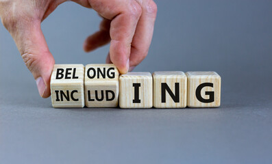 Including or belonging symbol. Businessman hand turns cubes and changes the word 'including' to 'belonging'. Beautiful grey background. Business and Including or belonging concept. Copy space.
