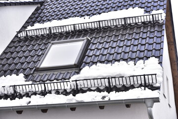 Schneefanggitter zur Vermeidung von Dachlawinen auf einem Ziegeldach mit Dachfenster montiert