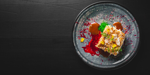 Layered cake with cream Napoleon in plate on wooden table background
