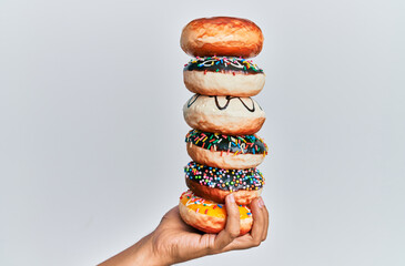 Hand of hispanic man holding tower of donuts over isolated white background.