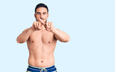 Fototapeta premium Young handsome man wearing swimwear rejection expression crossing fingers doing negative sign