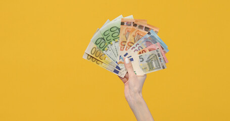 Female hands holding euro banknotes on a yellow background. Euro Money in woman hand. Euro cash background - obrazy, fototapety, plakaty