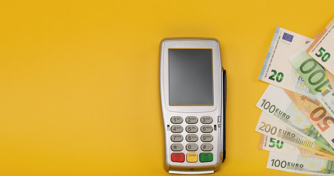 Euro banknotes and credit card reader machine. Euro cash money or Payment terminal isolated on yellow background.