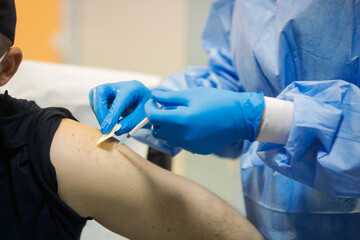 Details with a man getting an intramuscular injection with the Sars-Cov-2 vaccine in a hospital...