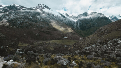Fototapeta na wymiar Dark landscape at Cordillera Blanca in Peru. Yanapaccha snowy peaks at 5000 m above sea level and lake.