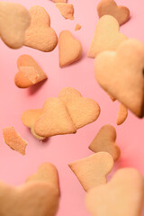 Flying homemade heart shaped cookies on pink background. Valentines day vertical greeting card.