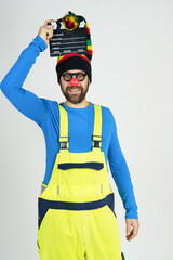 A clown in a bright suit holds a movie clapperboard in his hands.